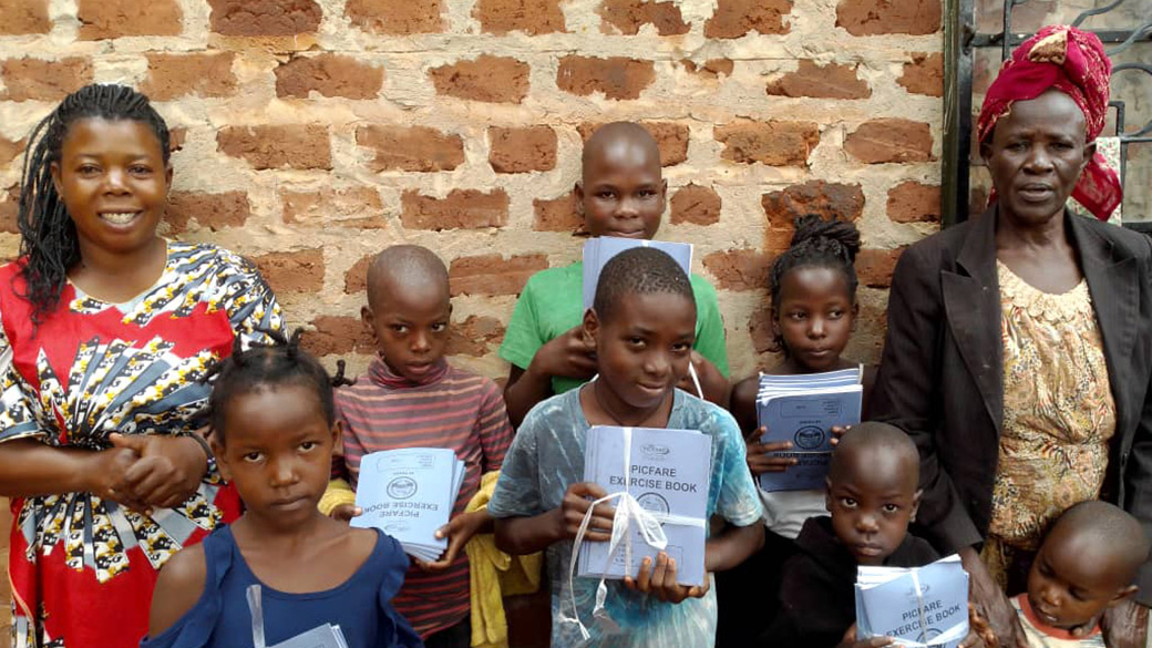 Waisen mit Schulunterlagen und Mitarbeiter auf einem Gruppenfoto.